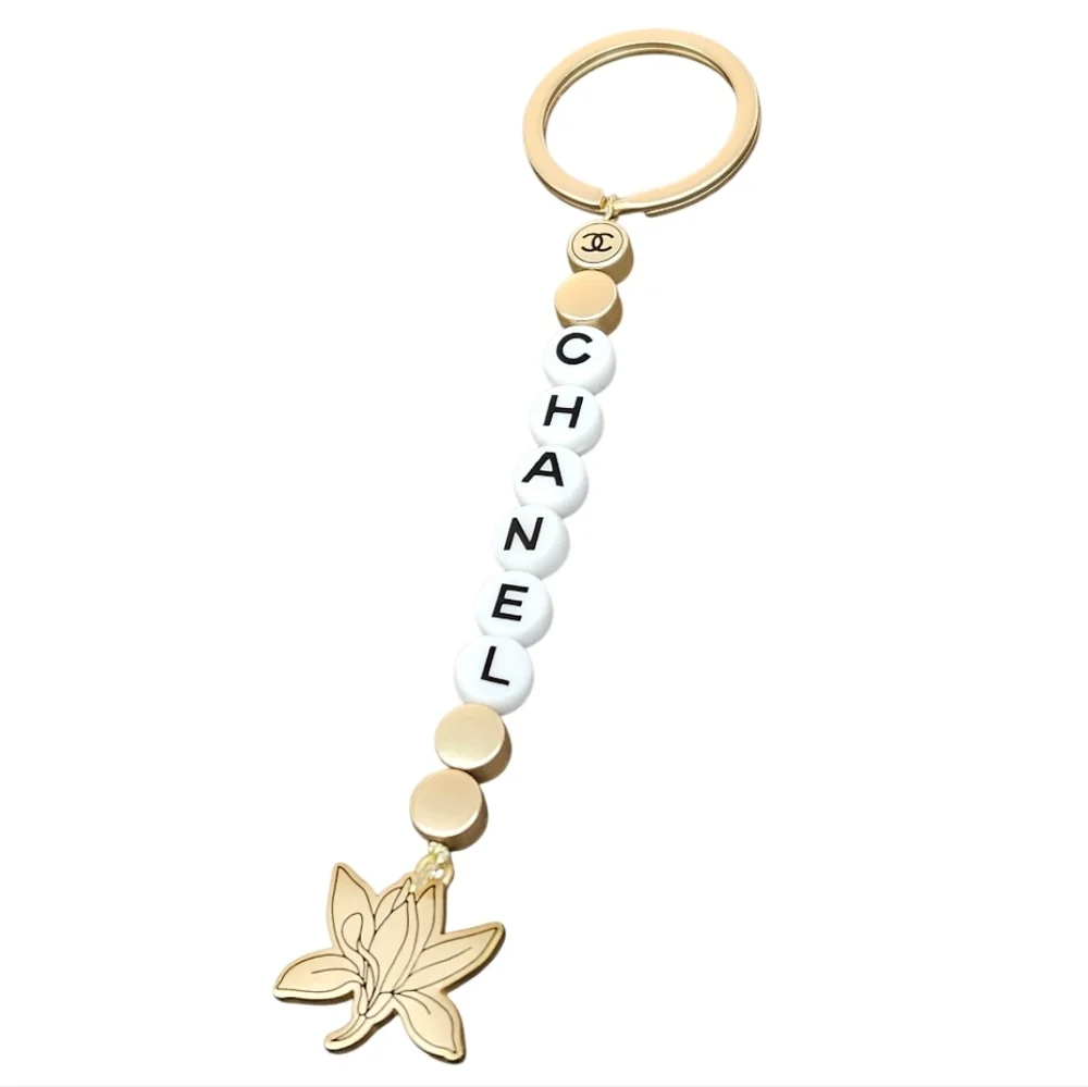 NIB CHANEL Sublimage Gold & White Beaded Keychain with Flower Charm